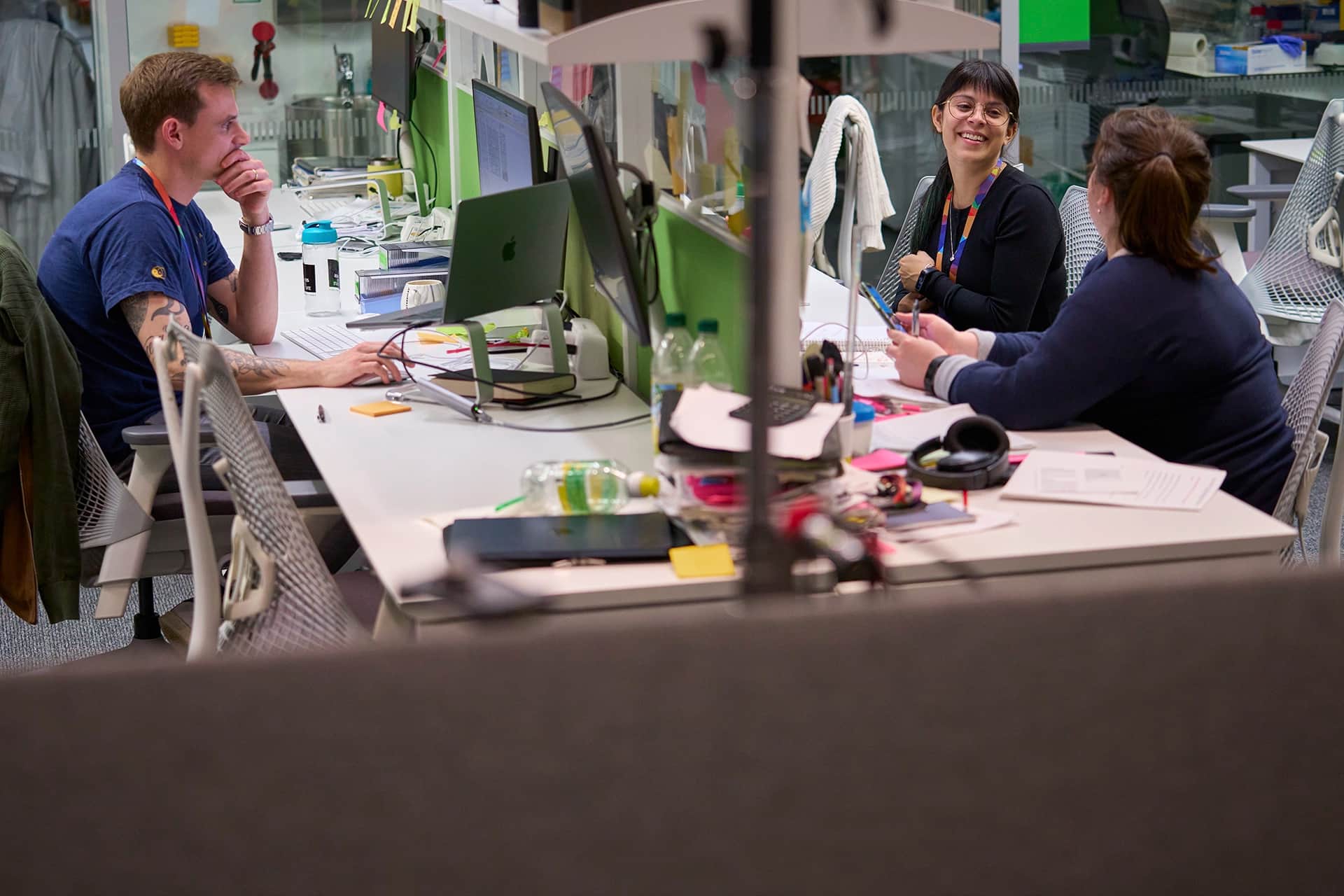 Three employees working at their desks in a busy office.