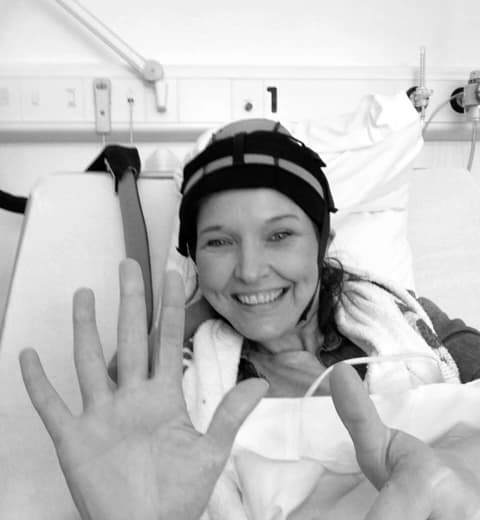 A woman waving from her hospital bed.