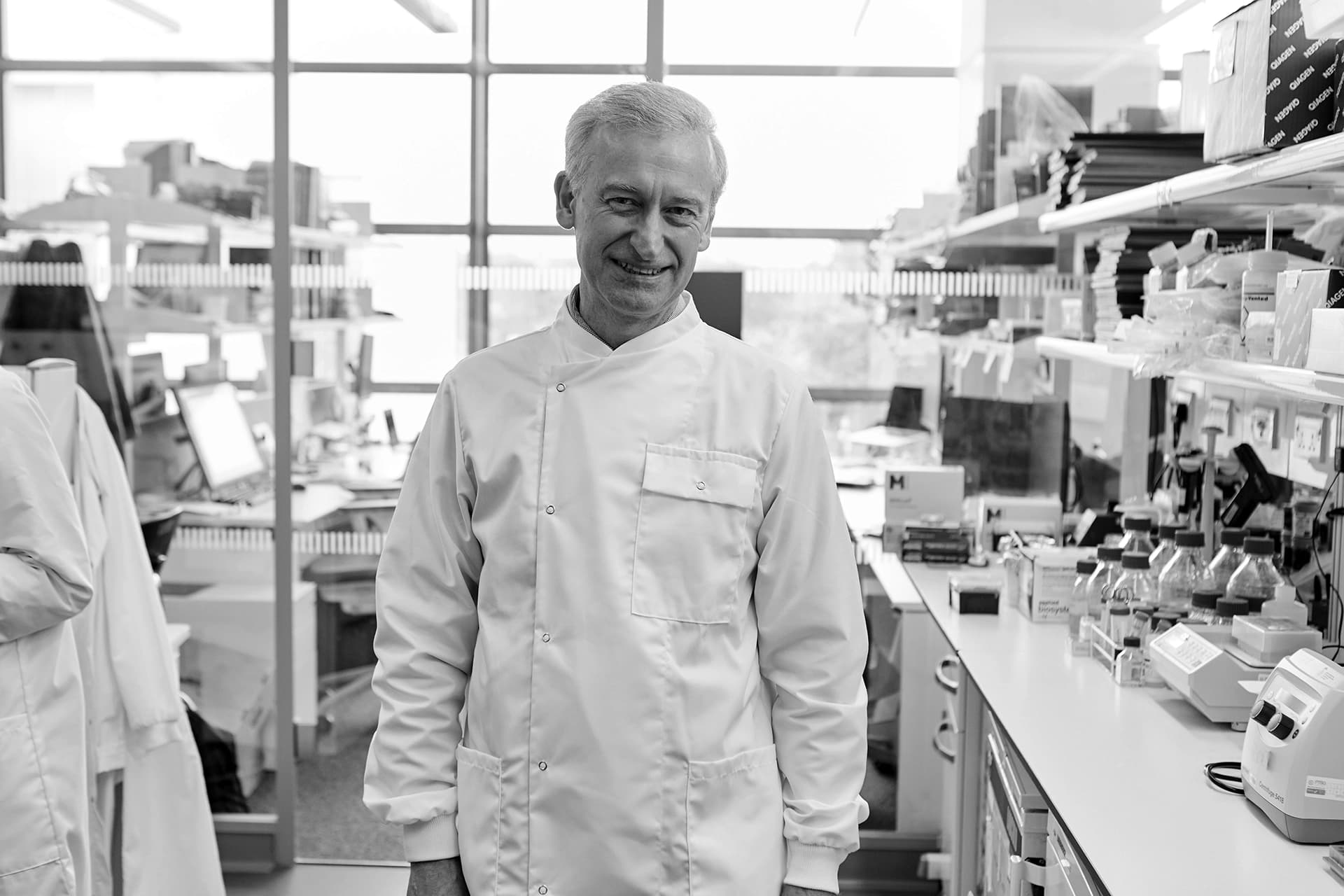 Julian Downward wearing a lab coat, standing in a research laboratory. 