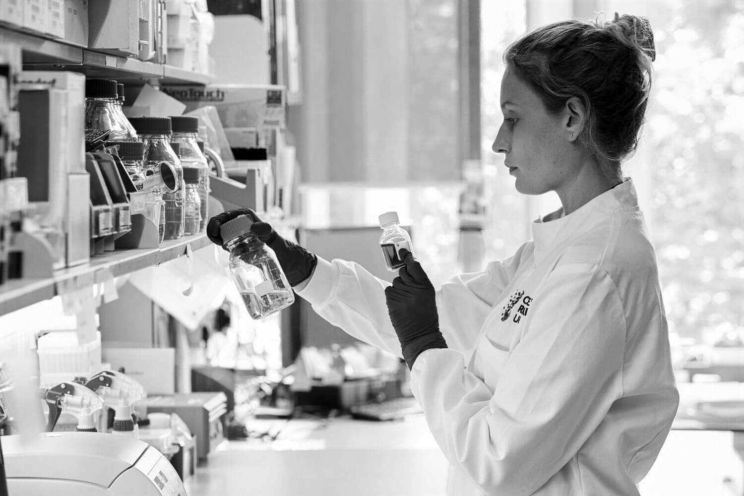 A female scientist in a research laboratory examines a liquid in a container.