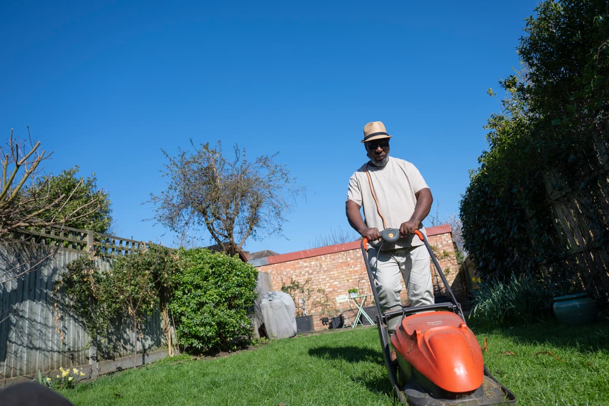 Man with a lawnmower on a sunny day.