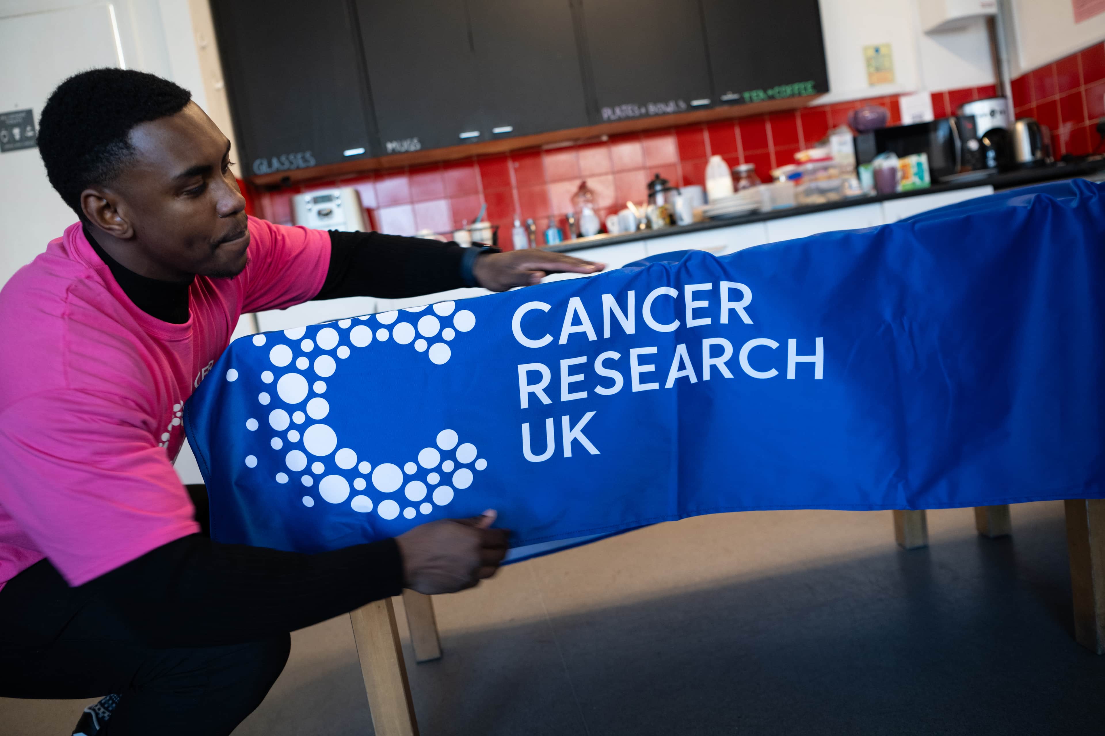 Man putting a CRUK branded table cover on.