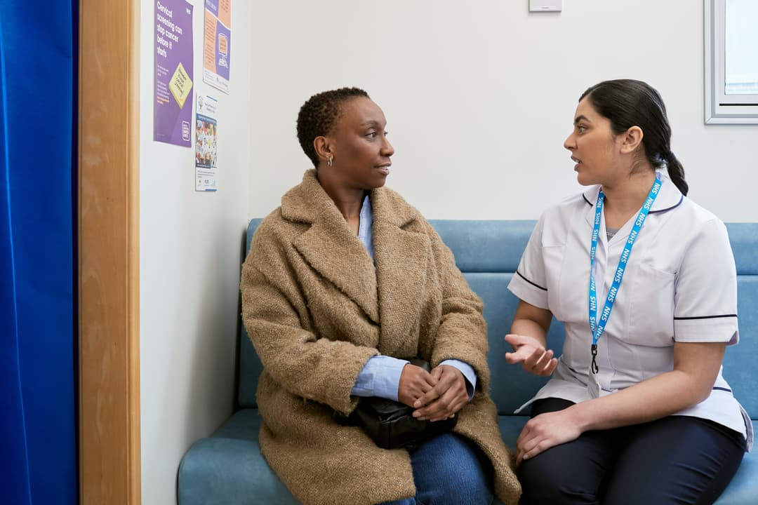 A patient and mamographer in the waiting room of a mobile breast screening unit.