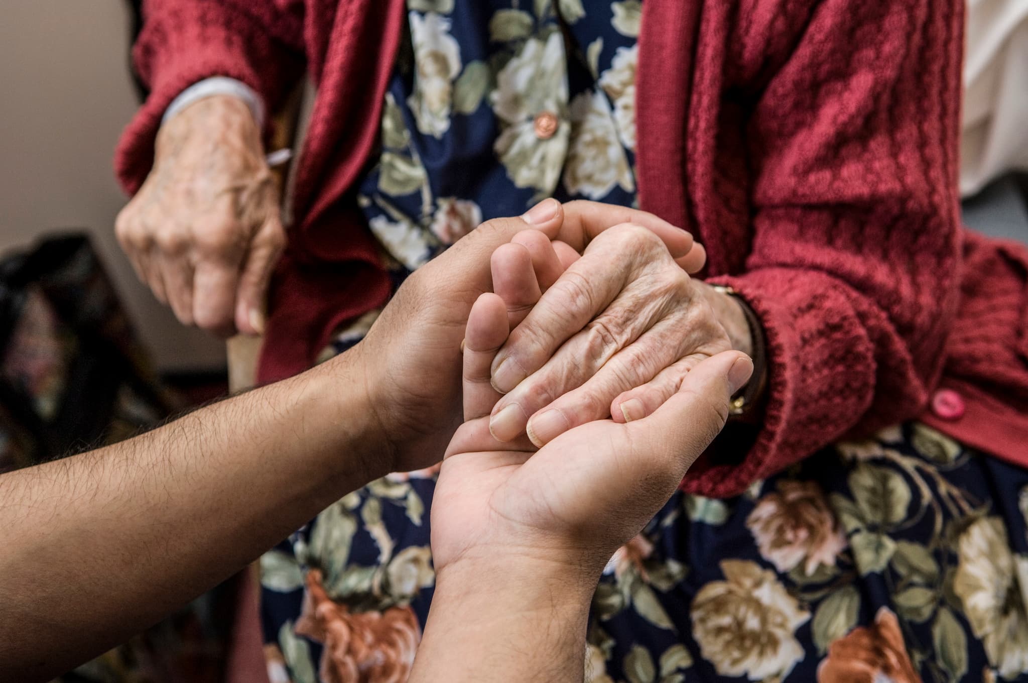 Someone holding the hand of what seems to be an elderly woman.