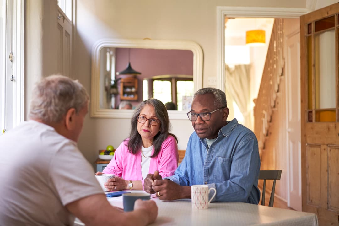 Photograph of people talking around a table.
