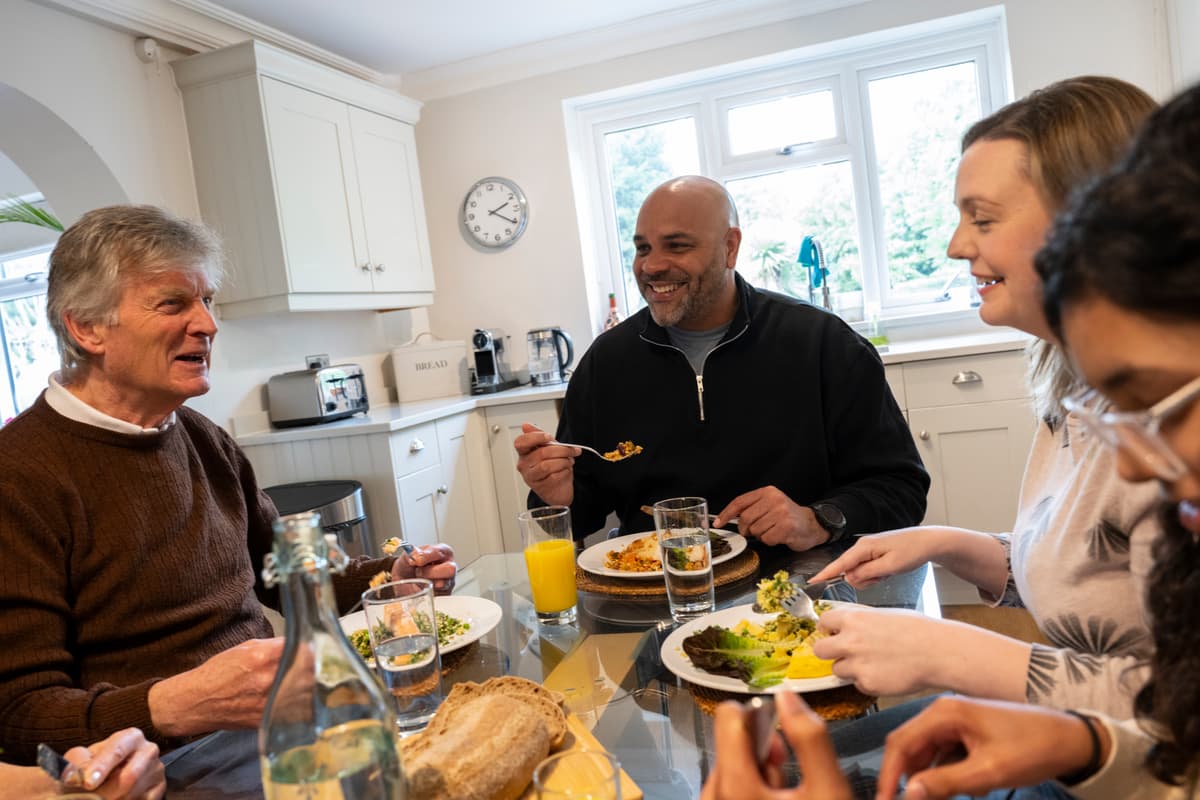 Four people sitting round a table eating food together.