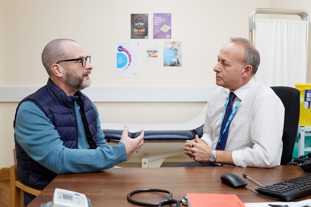 This photo shows a patient having a conversation with a GP about possible bowel cancer symptoms.