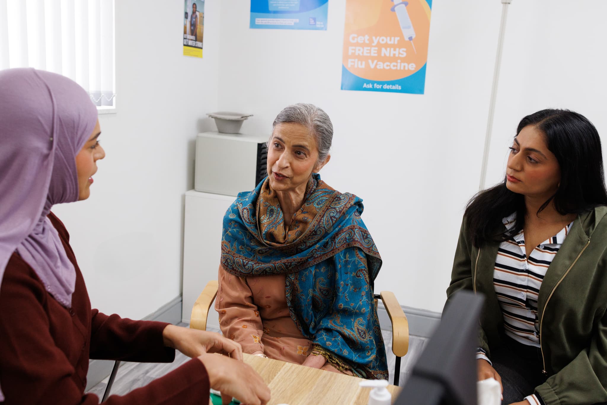 Photograph showing a patient and a relative sitting with a health professional.