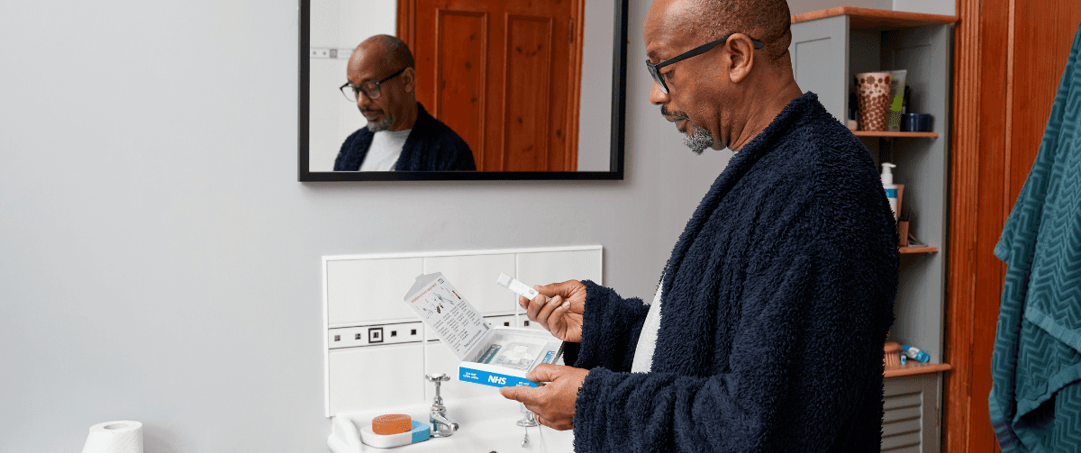 A photo of an older man looking at home testing equipment in bathroom.