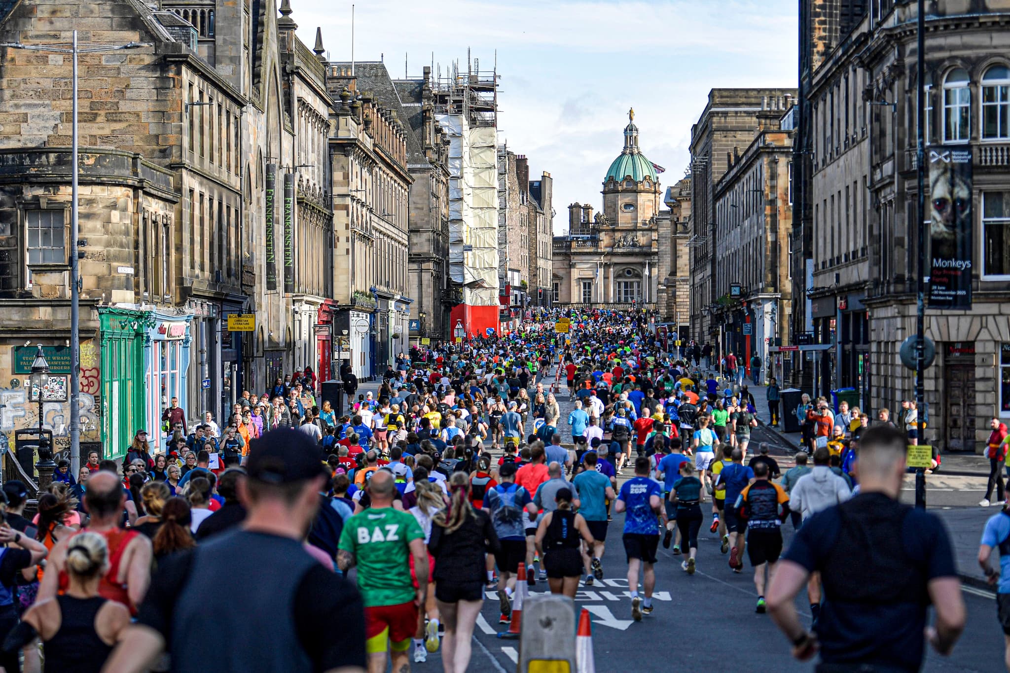 Crowds of Edinburgh Marathon runners, running up the Royal Mile in Edinburgh, towards the Bank of Scotland building.