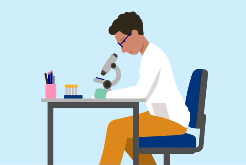 A picture of a doctor sitting at his desk looking through a microscope. There are also a tray of test tubes on the table.