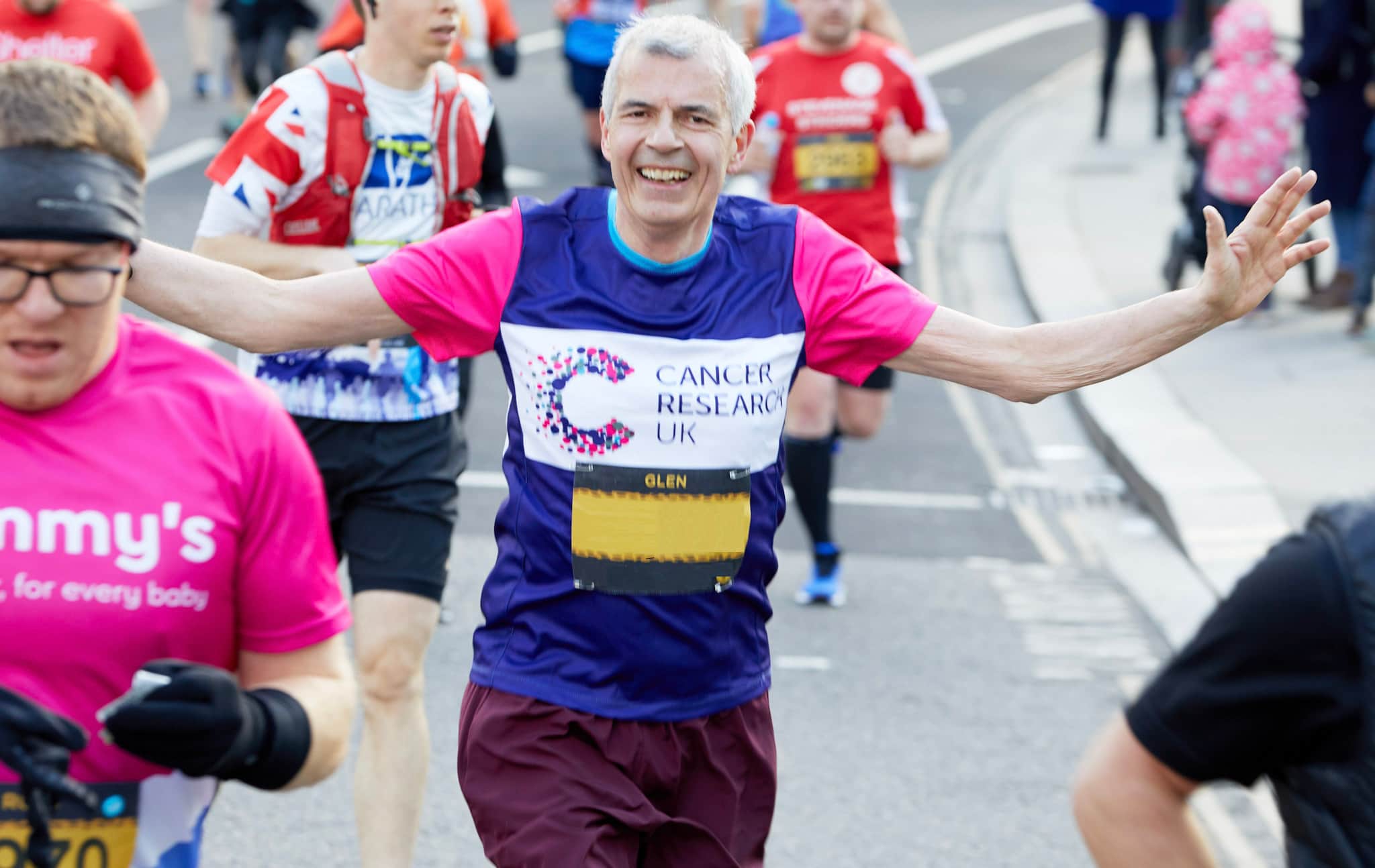 Image of a male runner wearing a Cancer Research UK t-shirt running and waving.