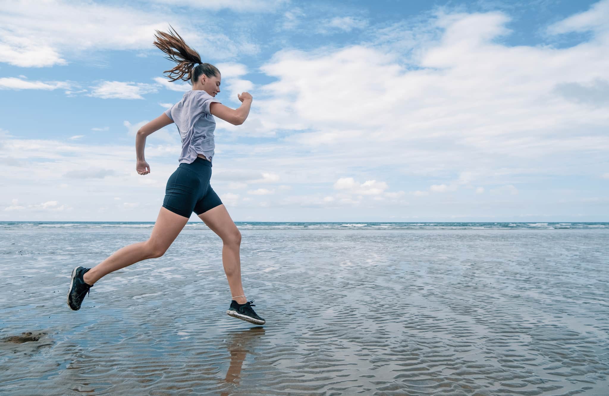 Woman running across a beachfront.