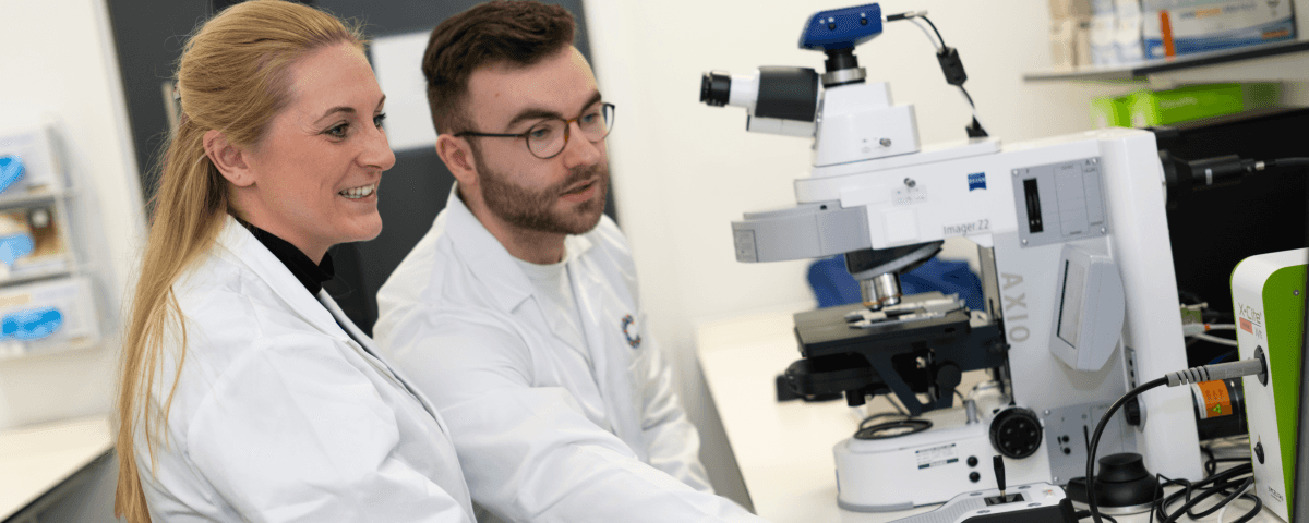 Two Cancer Research UK researchers looking at a screen together in a lab.