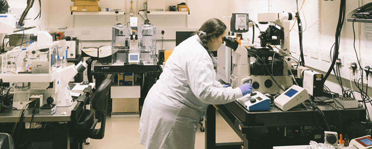Researcher looking into a microscope. Moments captured at the Cambridge lab with our researchers working in the lab alone.