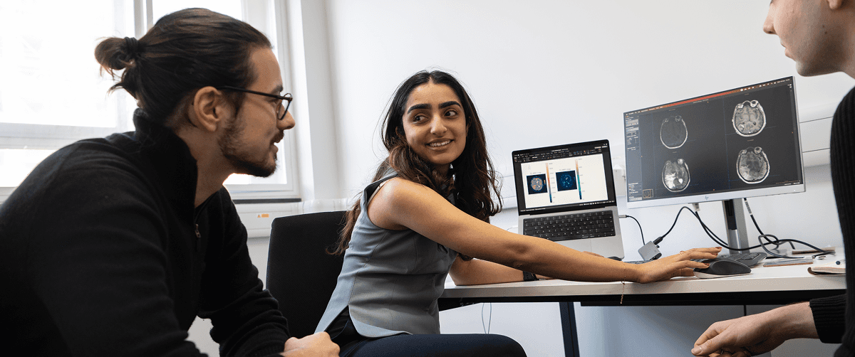 Researchers discussing brain images at a desk.
