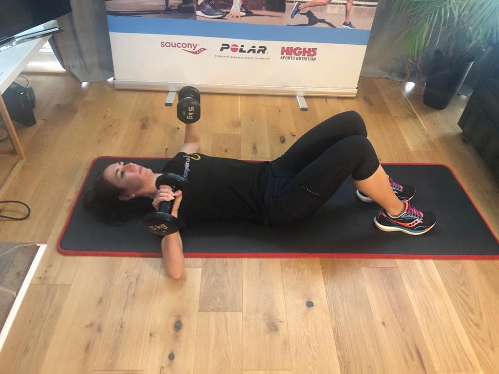 A person executing a dumbbell chest press.