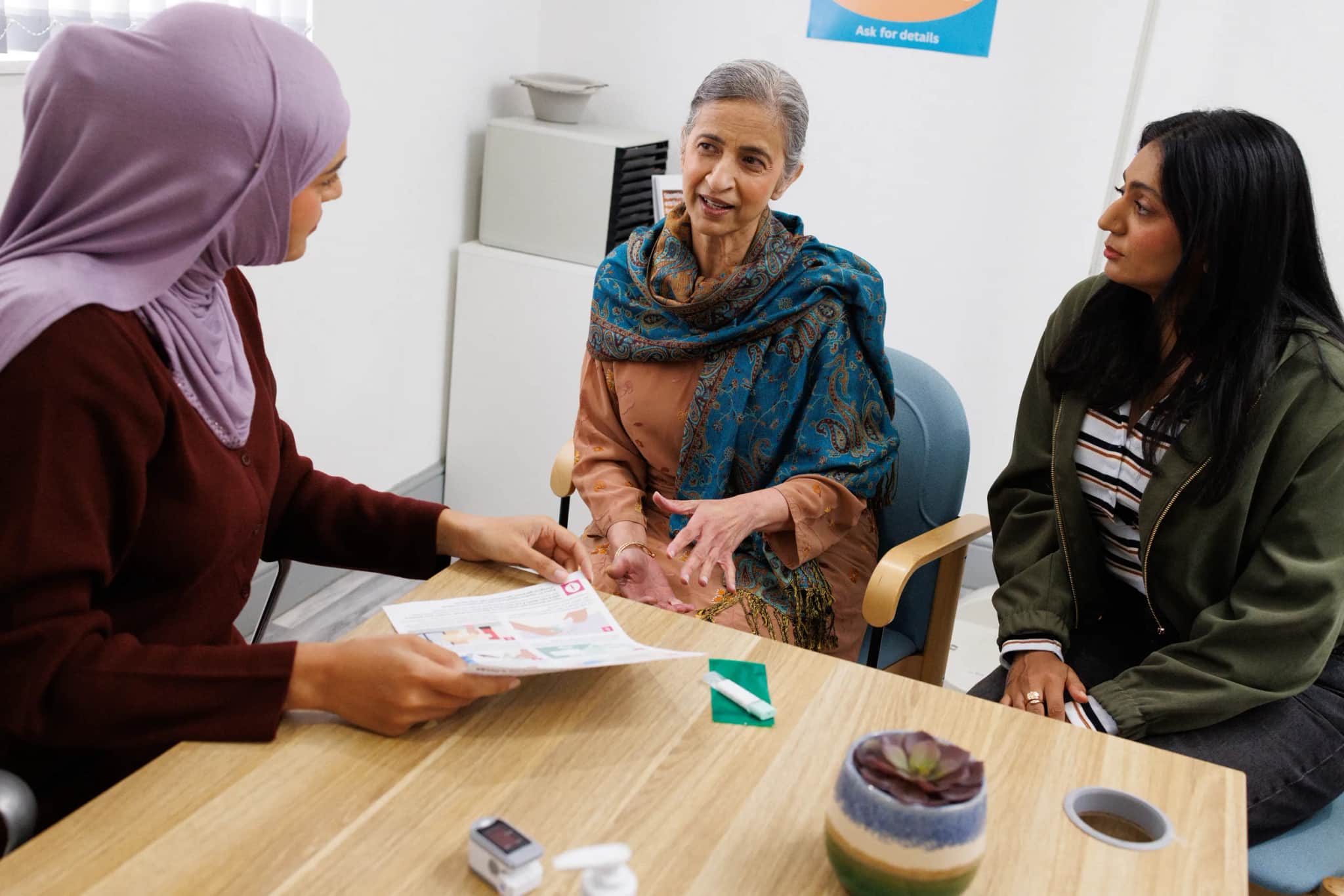 Doctor at the GP surgery talking to the patient and her carer.