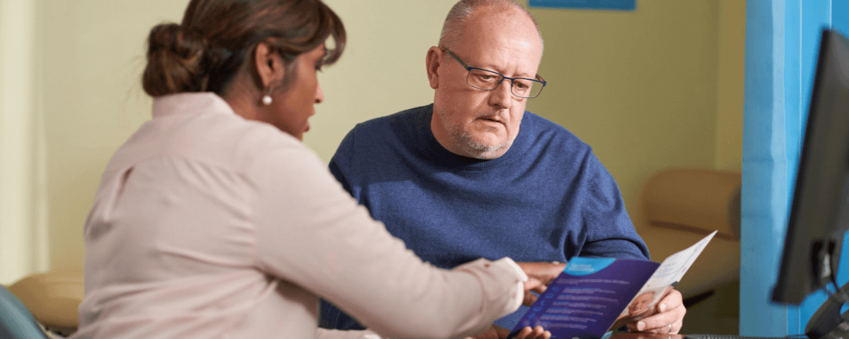 A GP explains the information included in a leaflet to a man with a cancer diagnosis.