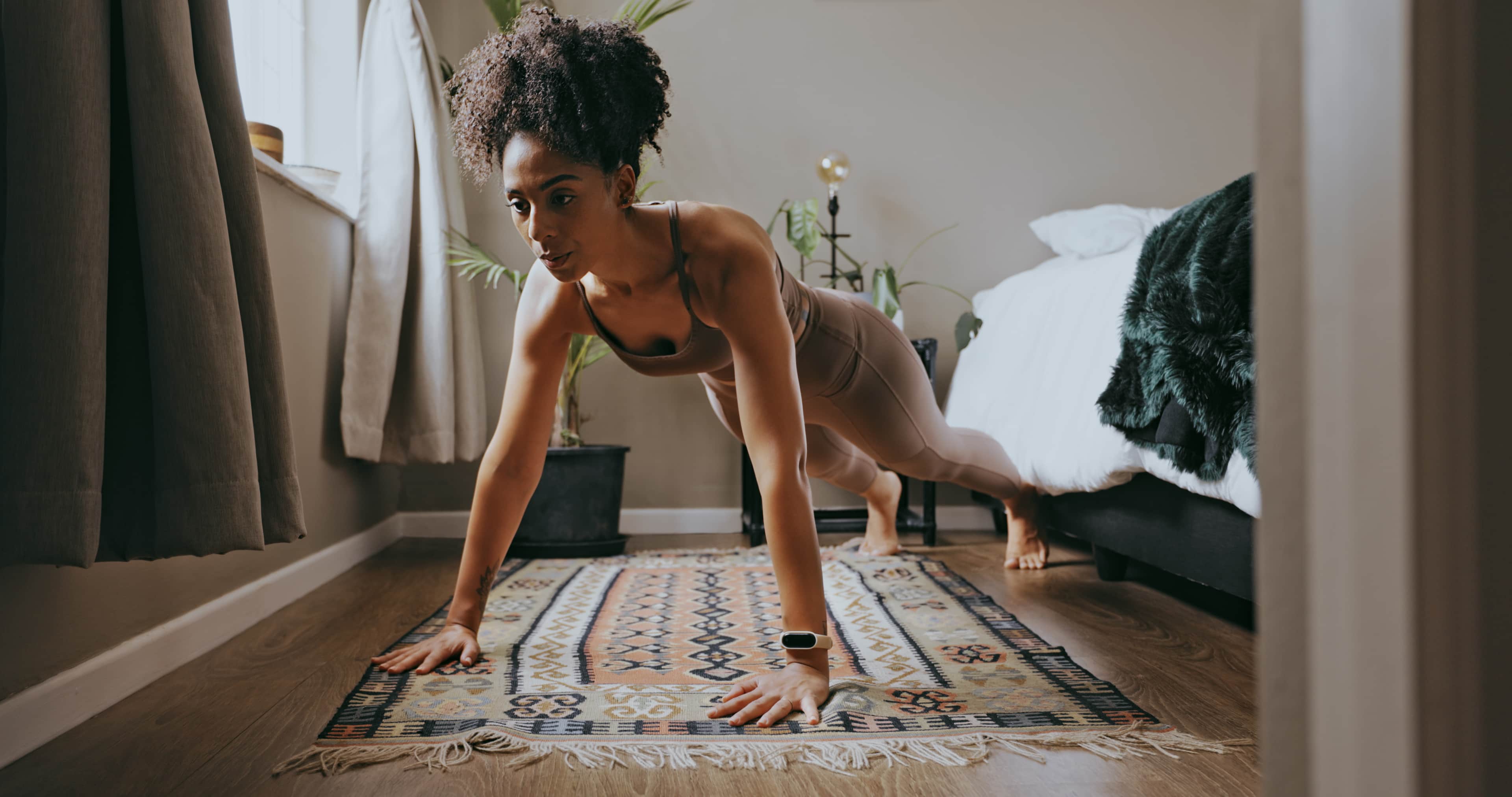 Low-shot of a woman doing a push-up in a bedroom setting.