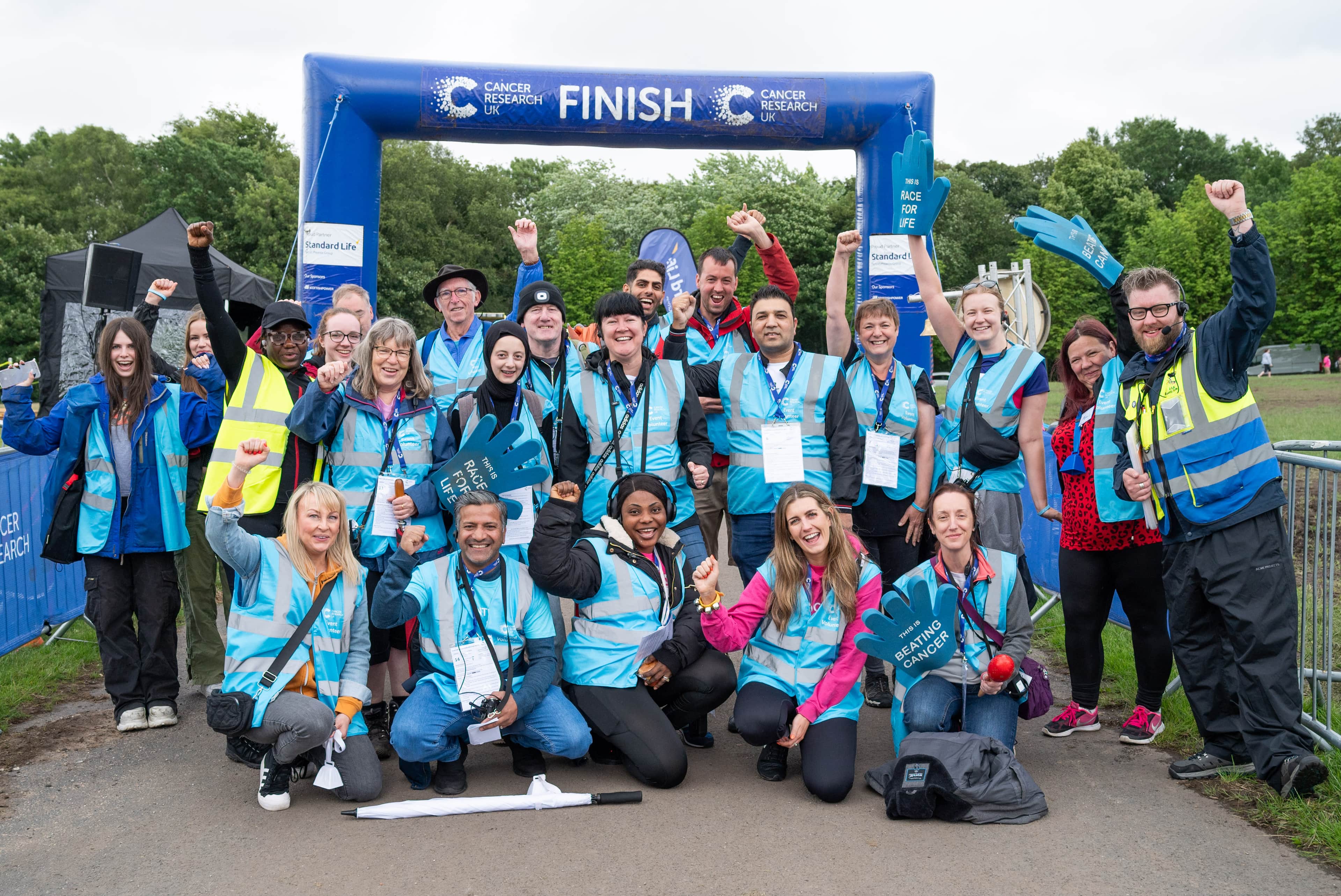 A group of event volunteers at the finish line of a CRUK event.