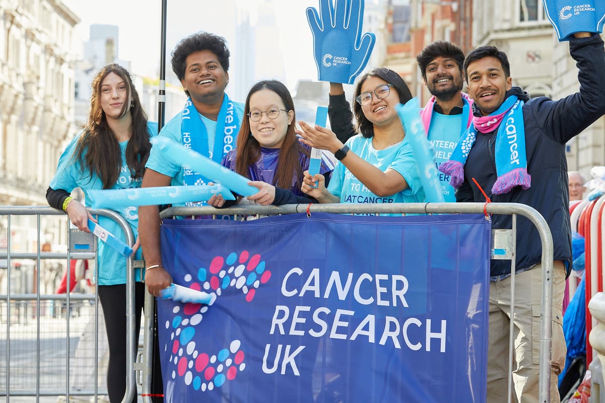 A photo of a Cancer Research UK volunteer showing the way to a runner.
