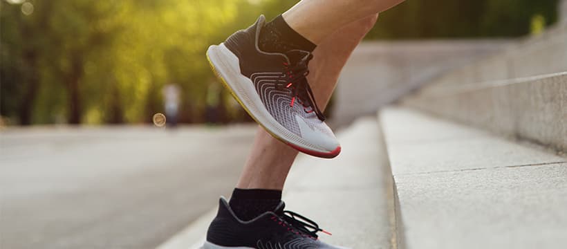 Close-up shot of someone's feet running up stairs in a pair of sports trainers.