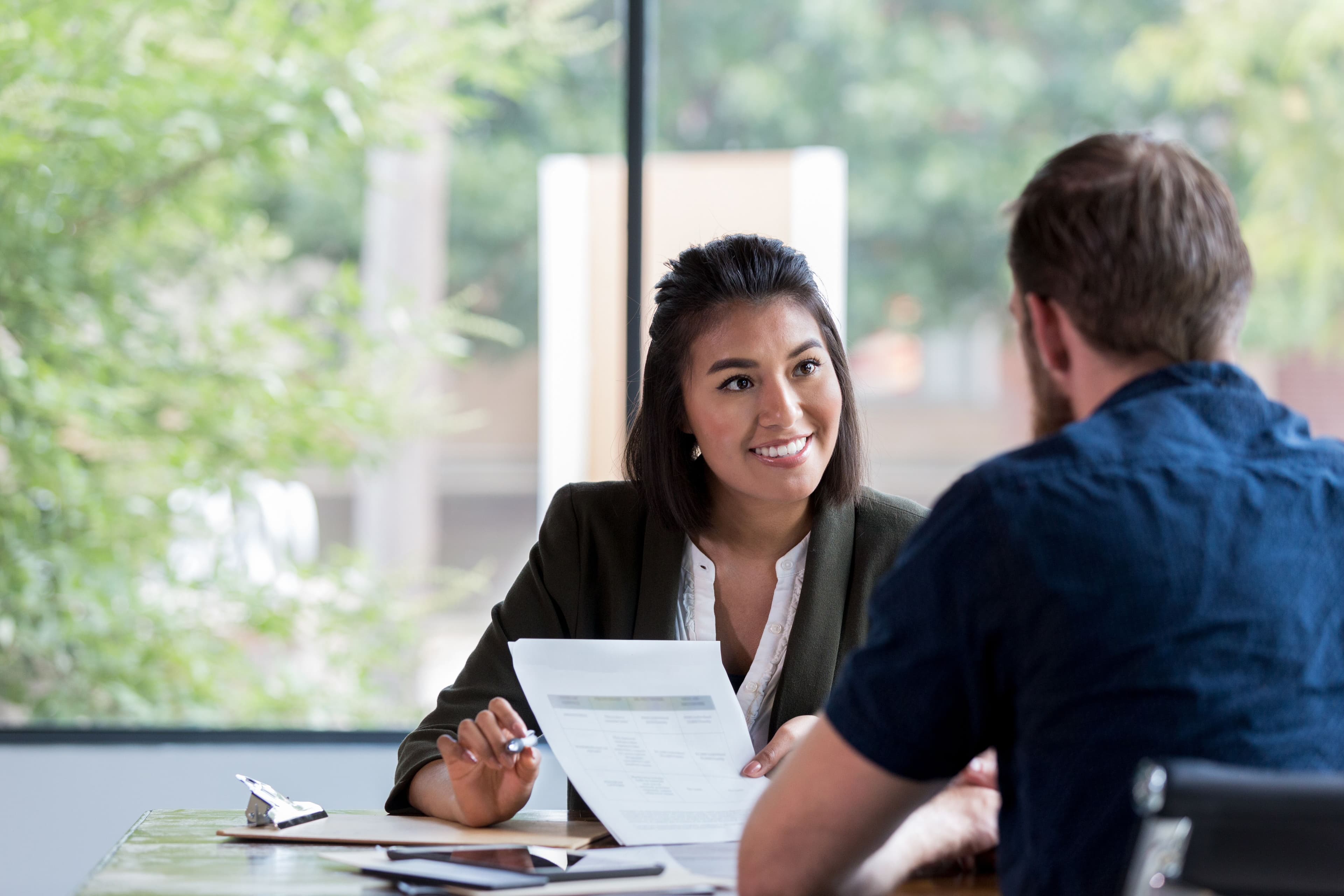 A legal professional is smiling at her client as they review files during a meeting.