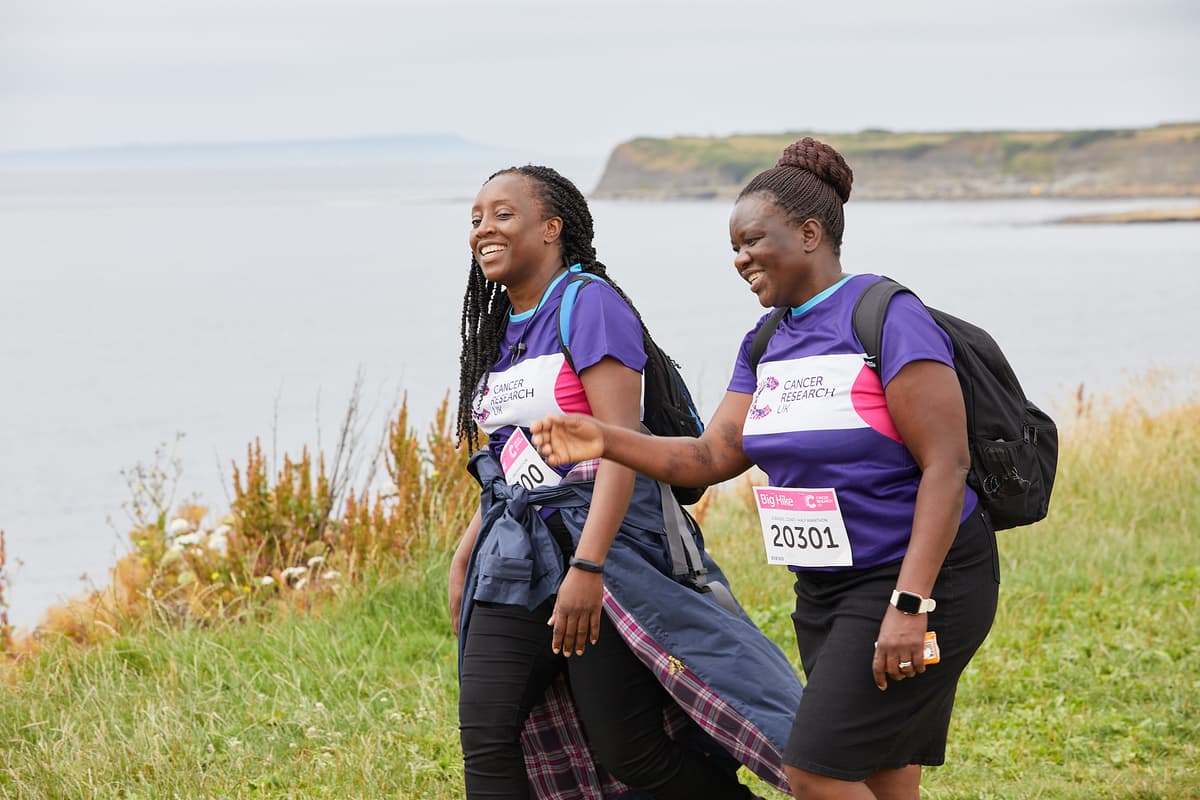 two women along a coastal line laughing.