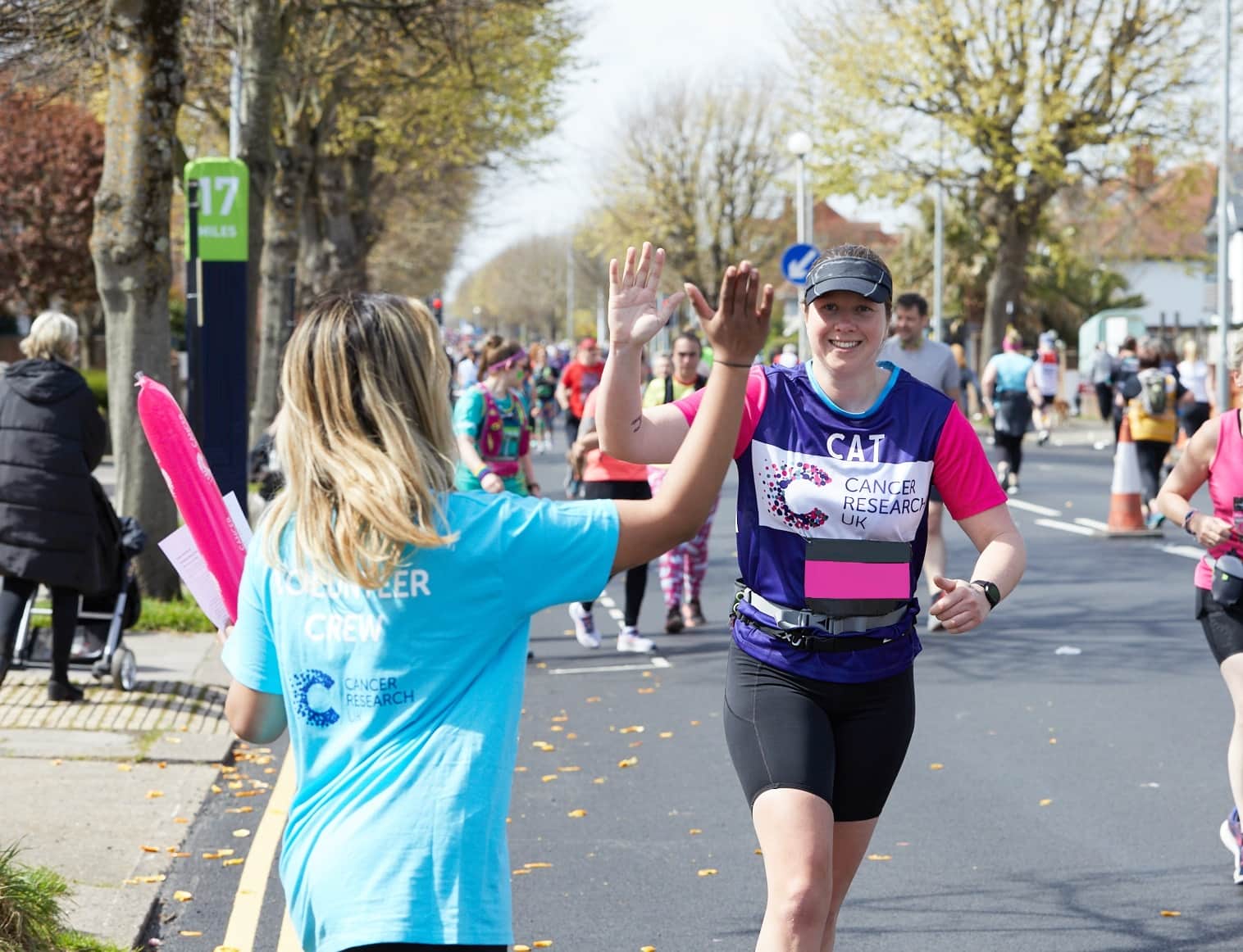 Supporter running in Brighton Marathon 2022 and going in for a high five with a member of the volunteer crew.
