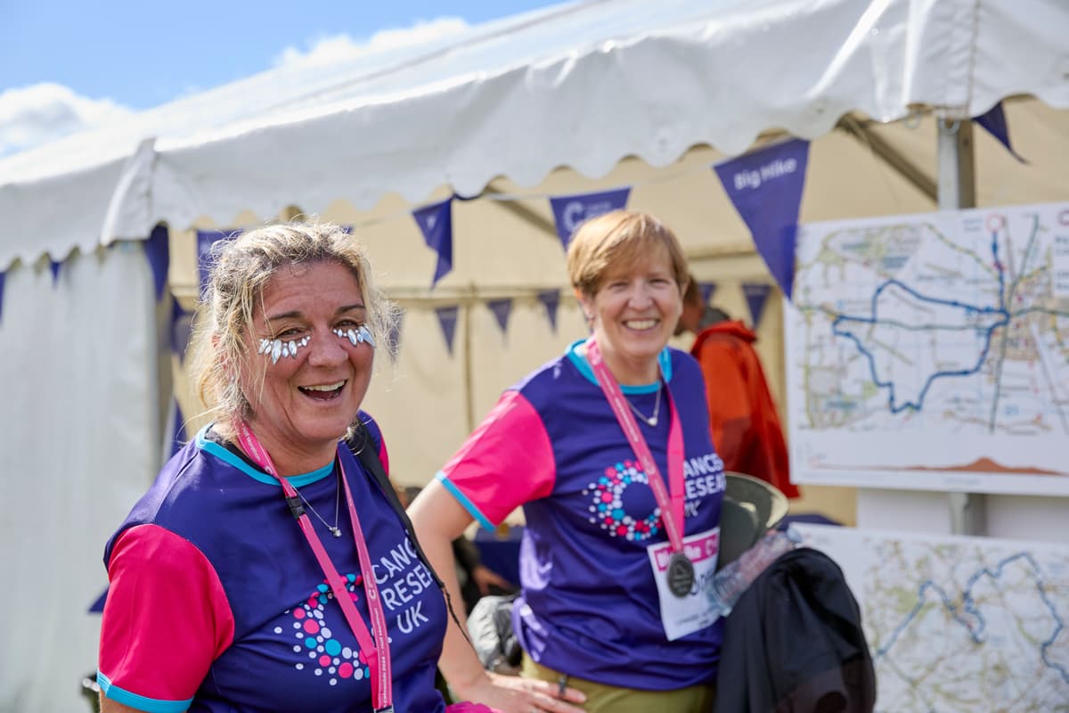 two women smiling wearing their Big Hike medals and Cancer Research UK t-shirts.