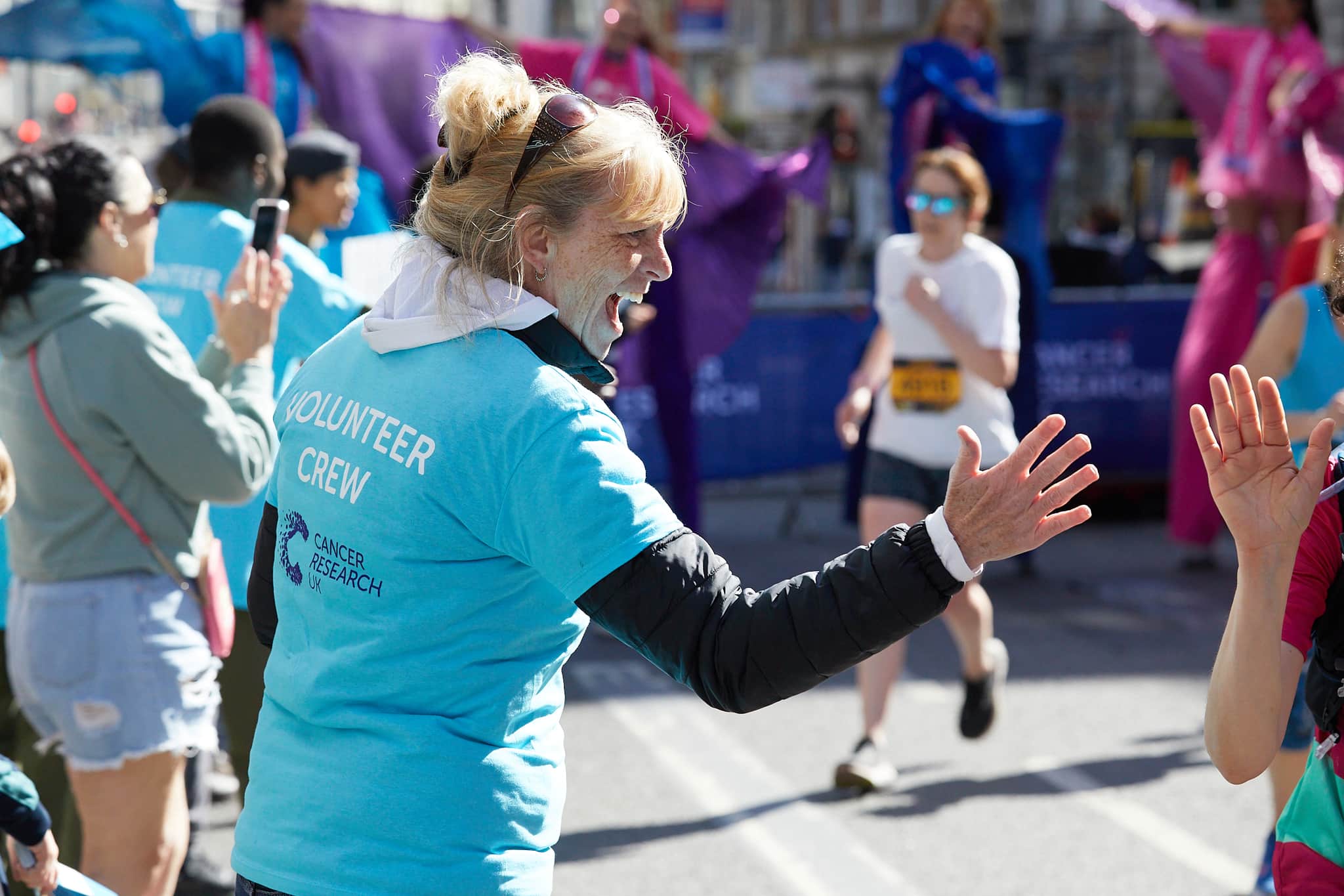 Event volunteer cheering on and high fiving event participants.