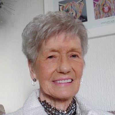 A woman with short cropped blonde hair, smiling, facing the camera.