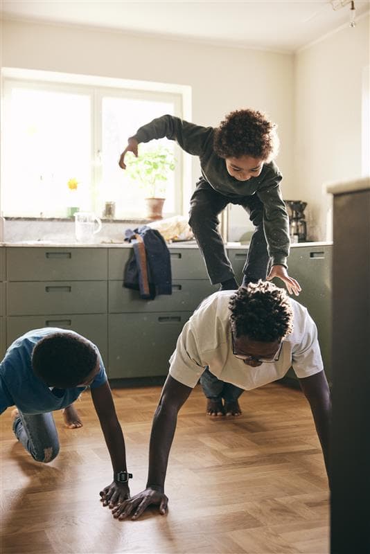 Man doing a push-up with a child on his back laughing.