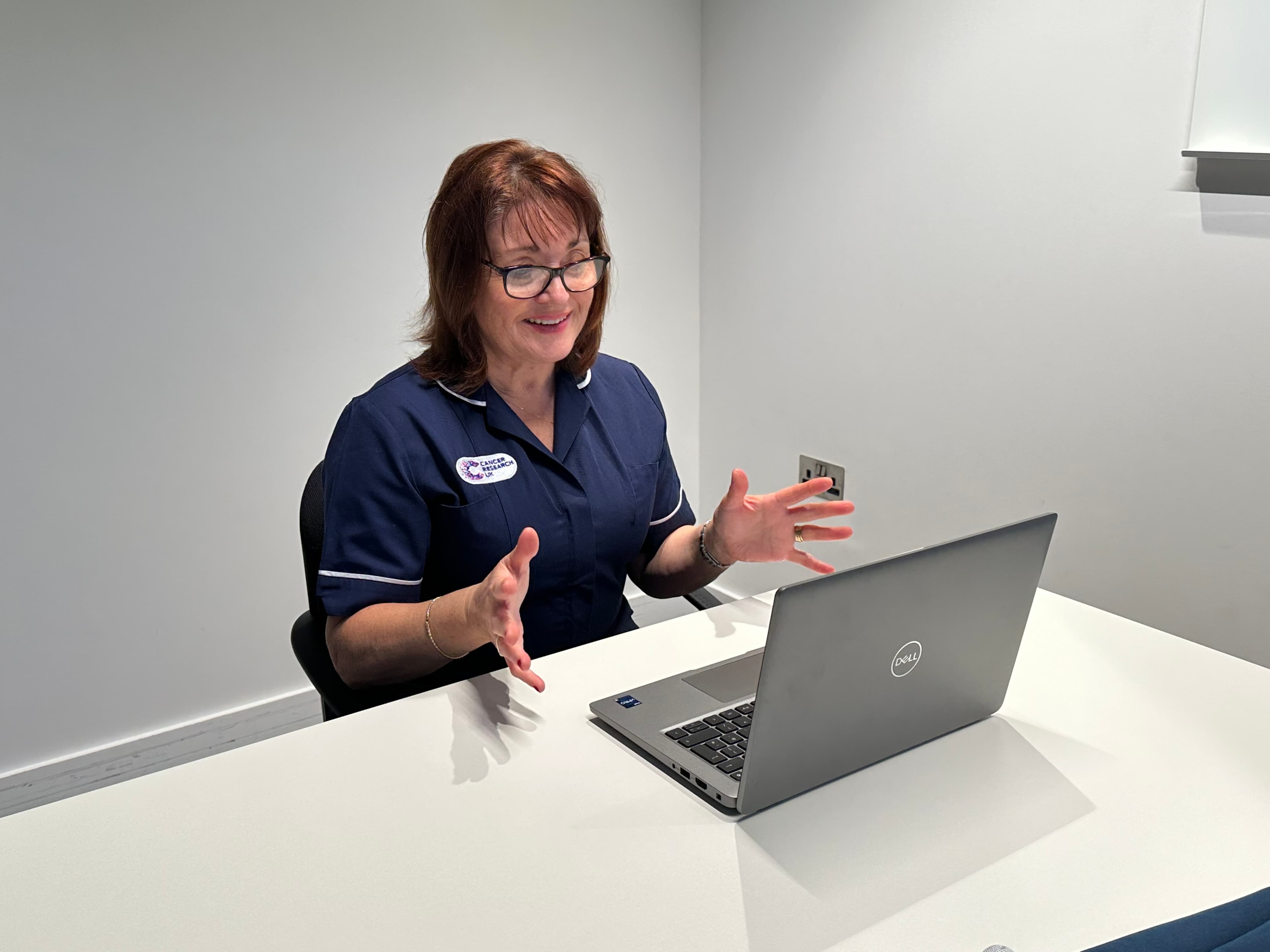 Medical professional sat at a laptop delivering a webinar.