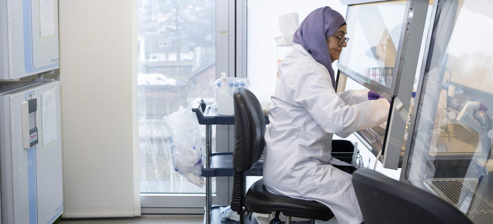 A researcher working by a fume hood in a lab.