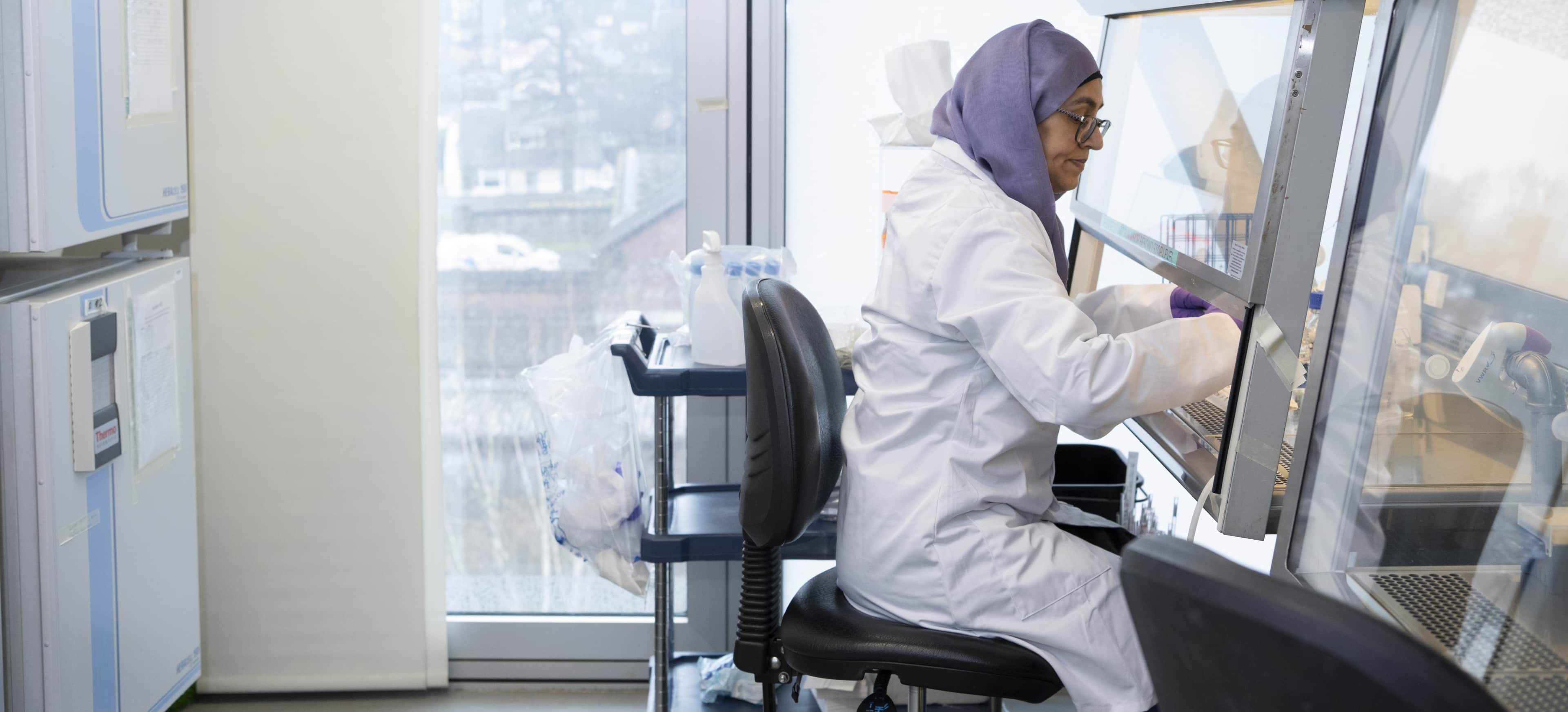A researcher working by a fume hood in a lab.