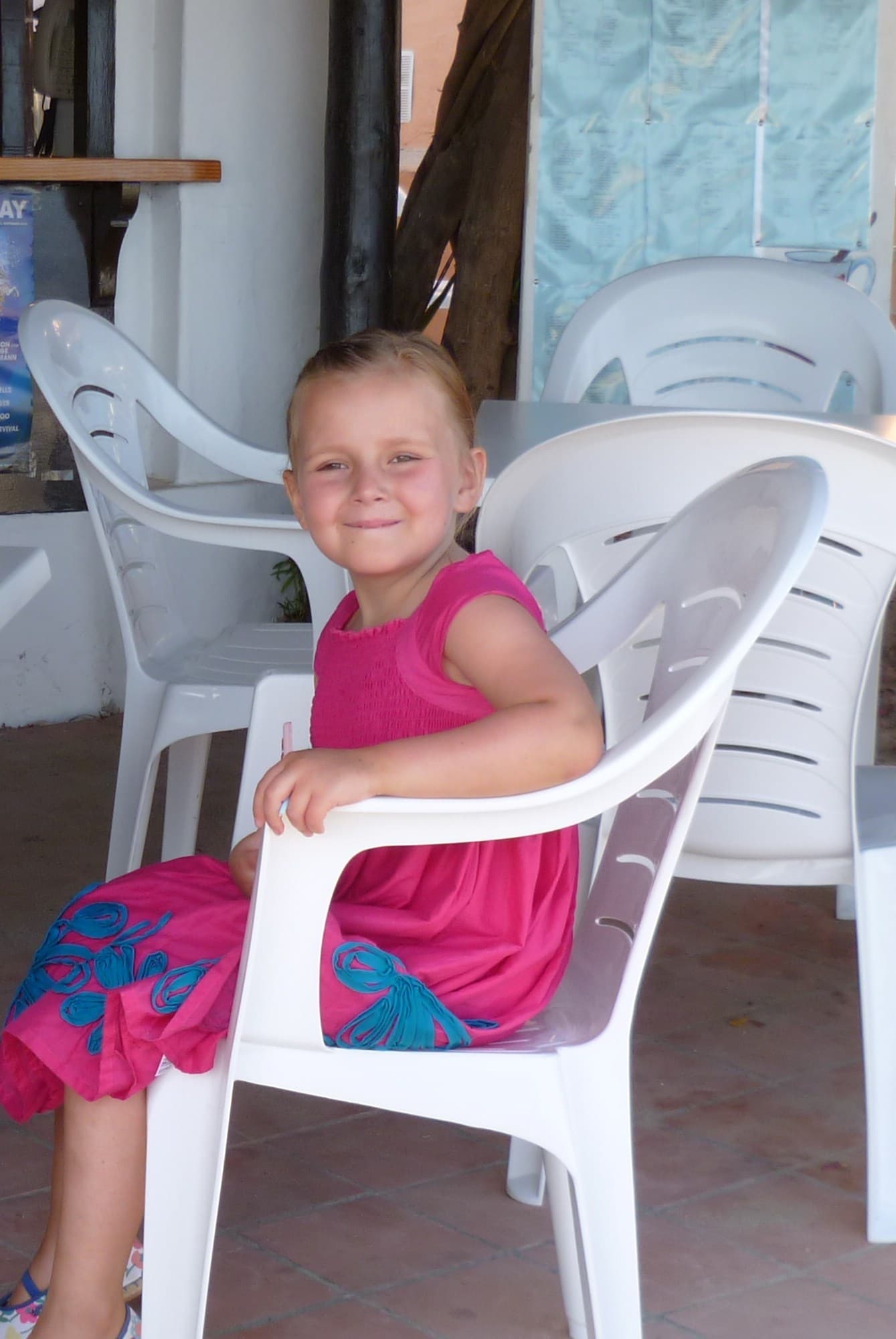Katie, a leukaemia patient, wearing a pink and blue dress and smiling at the camera.