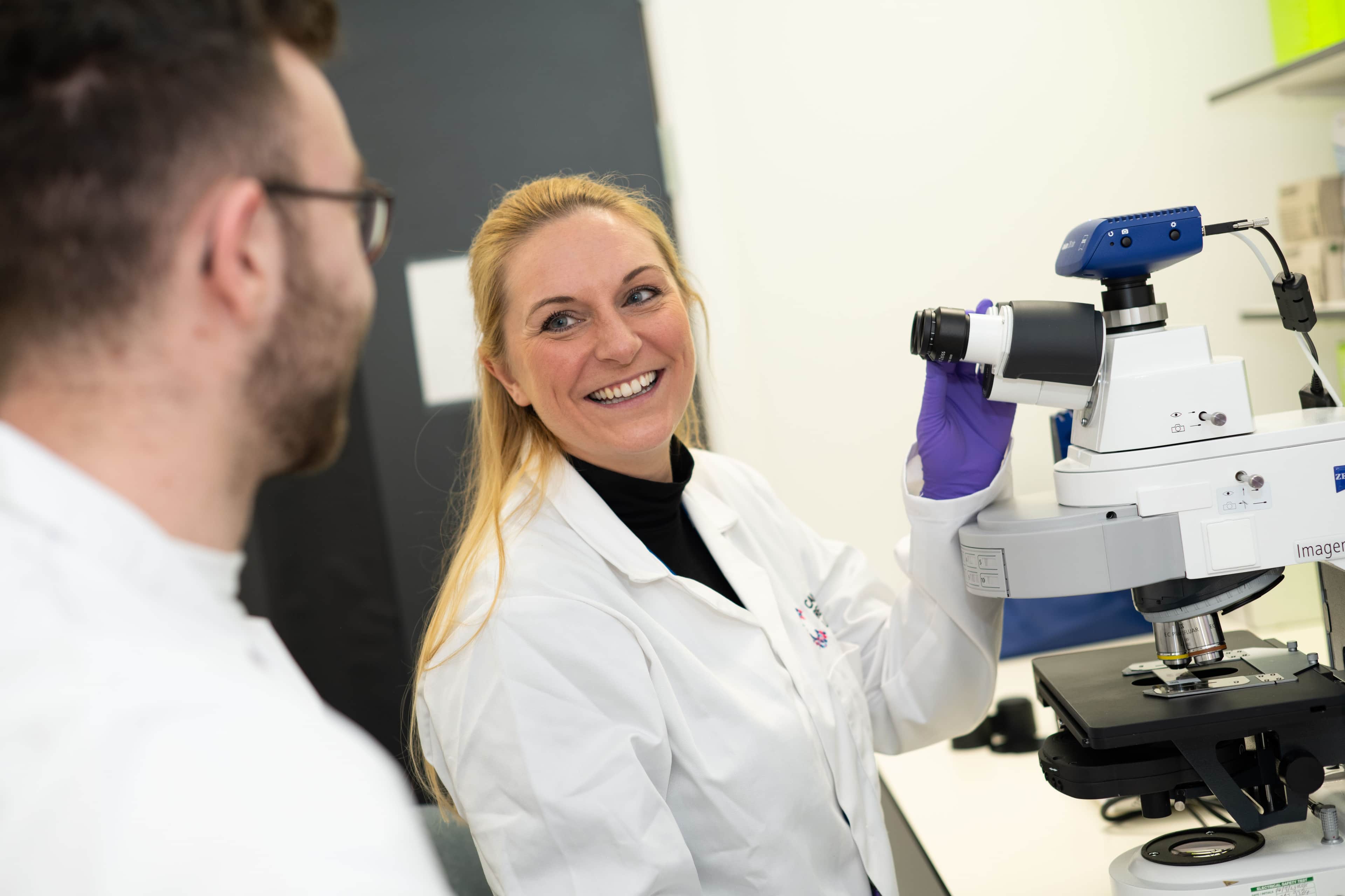 Two researchers working in a lab, smiling.