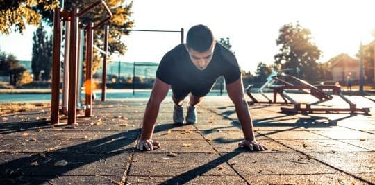 Man doing a push up outside in sunshine.