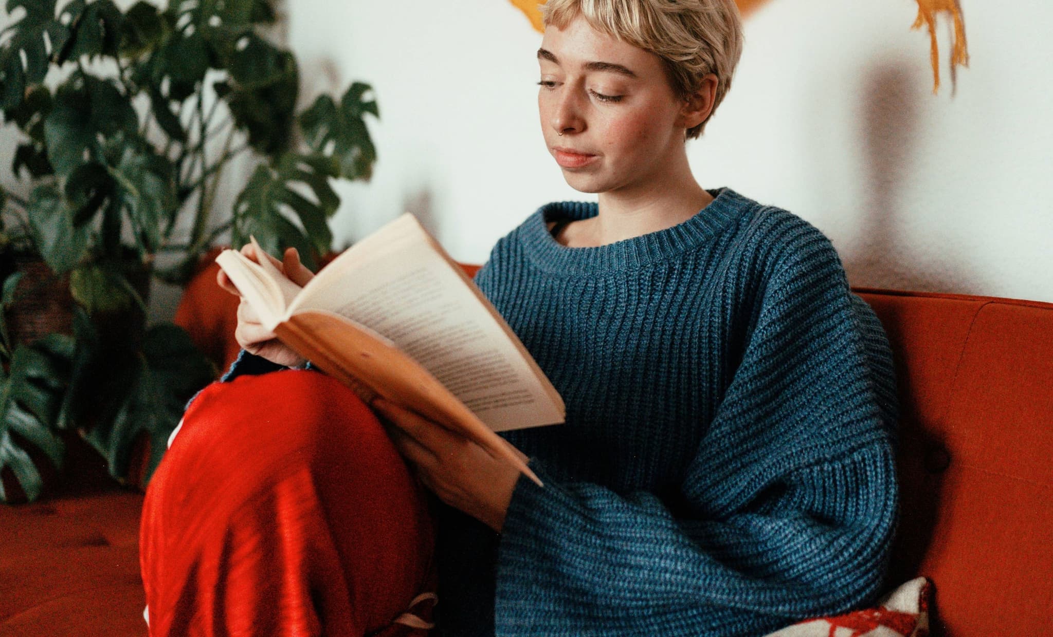 Woman sitting on couch reading a book.