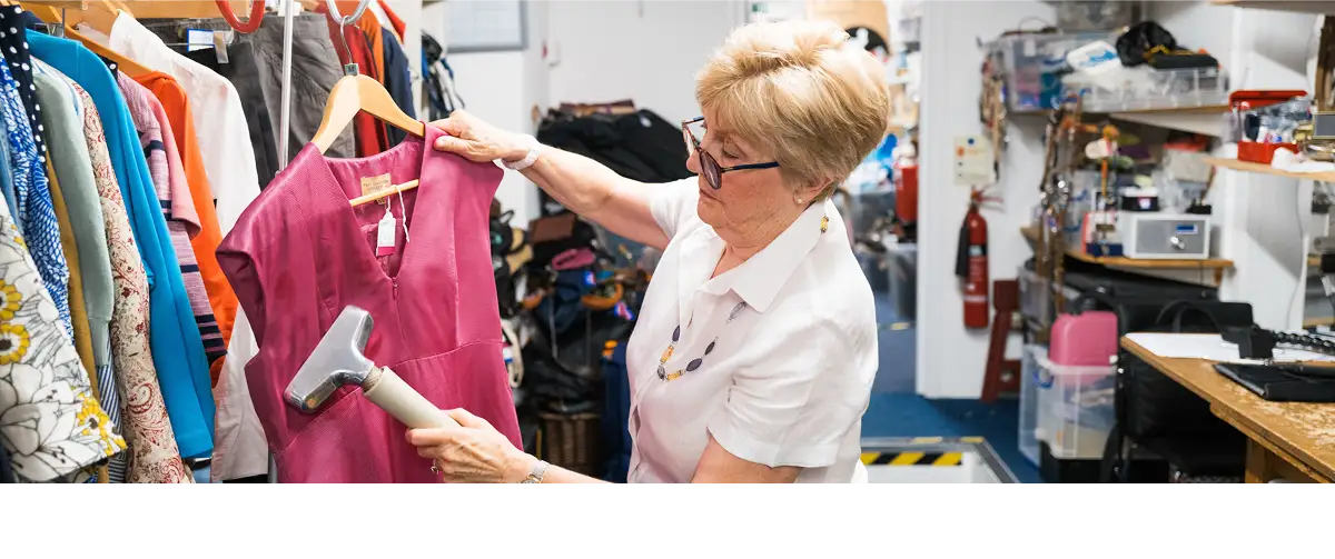 A photo of a Cancer Research UK shop volunteer steaming a shirt.
