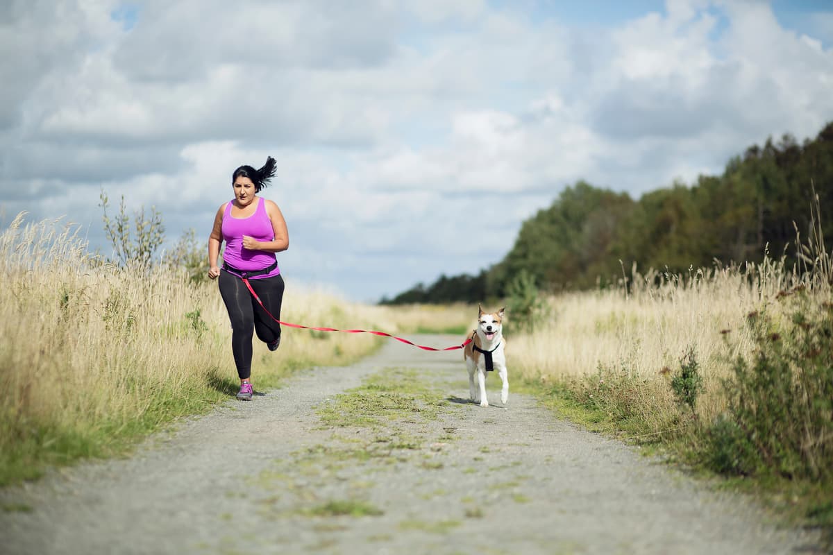 A person running outdoors with a dog.