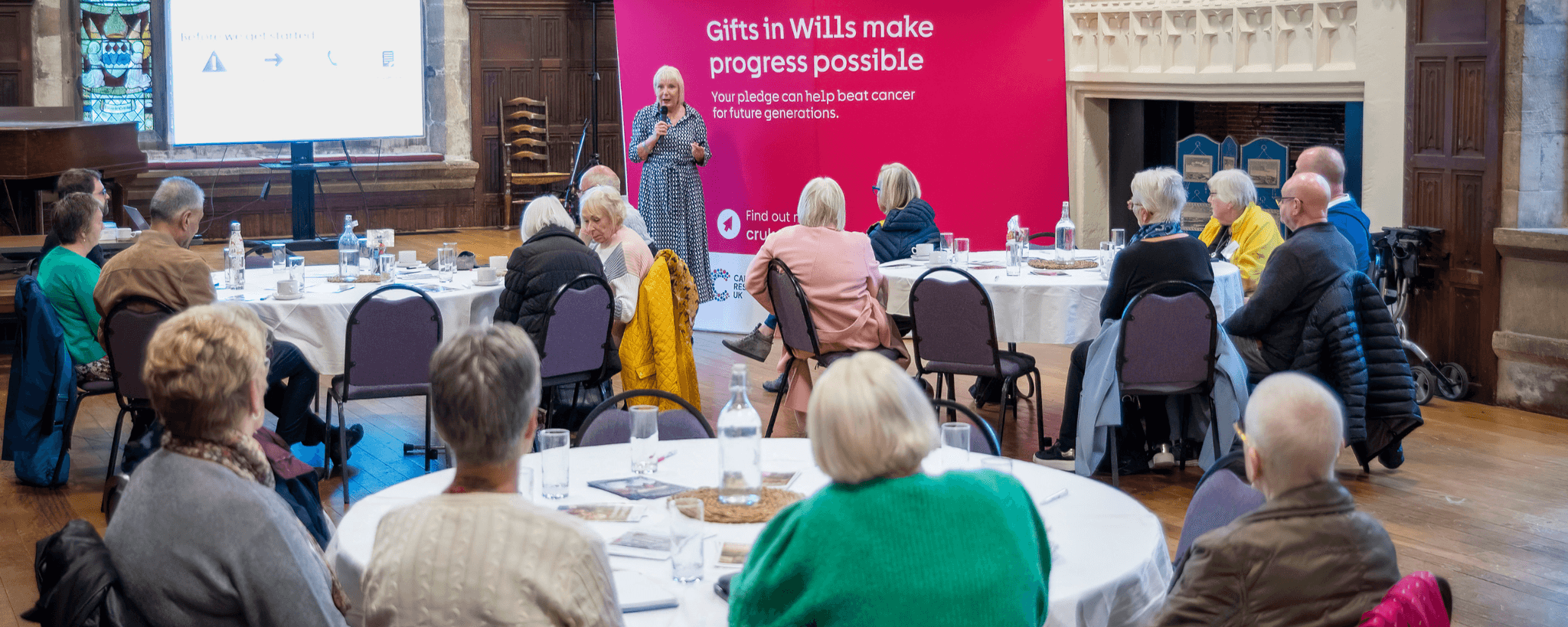 A group of people attending a Legacy Inspire event with a speaker presenting.
