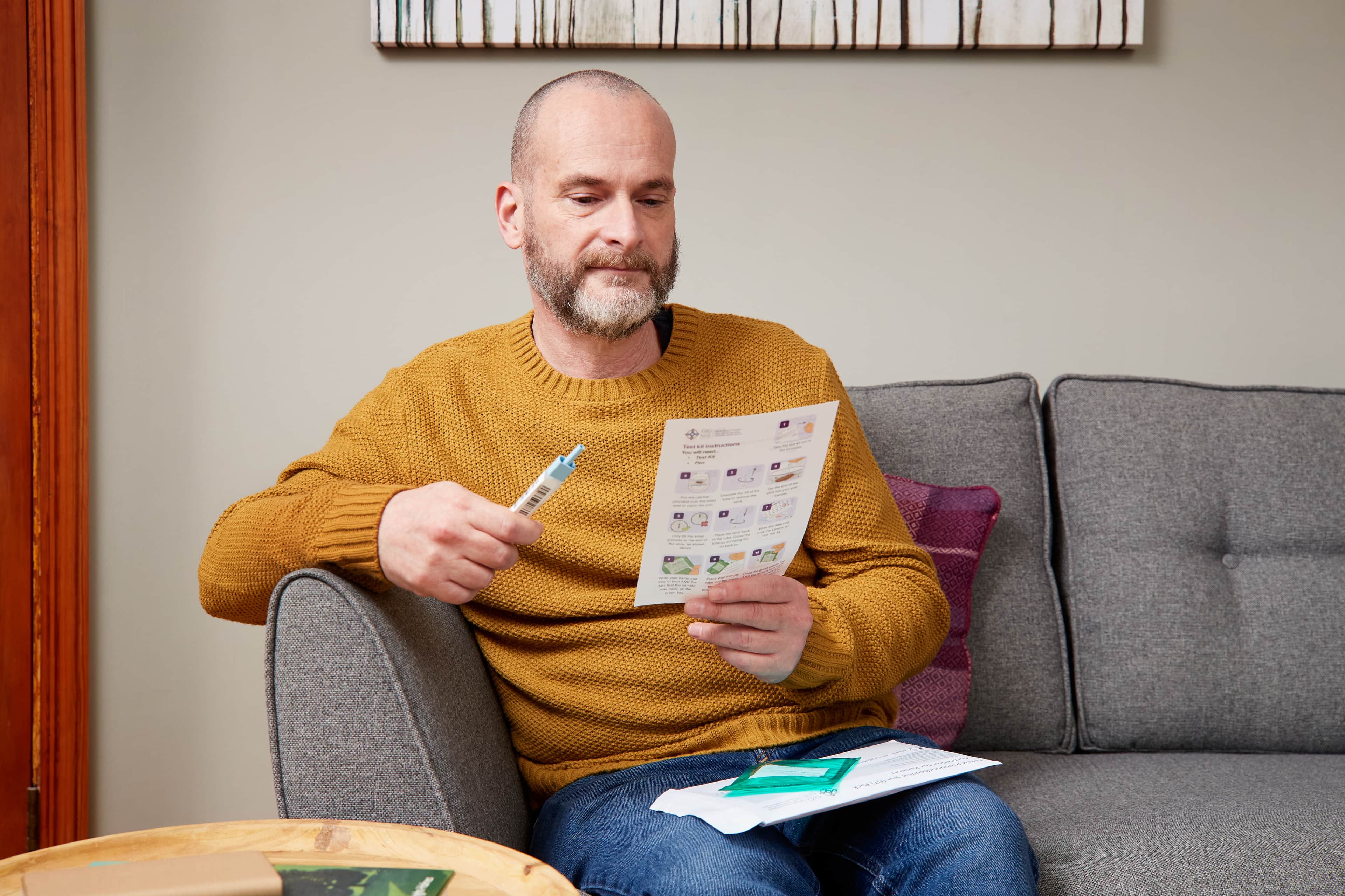 This photo shows a man using a Faecal Imunochemical Test (FIT) kit from Wales.