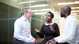 Three people sitting down and conversing in the office